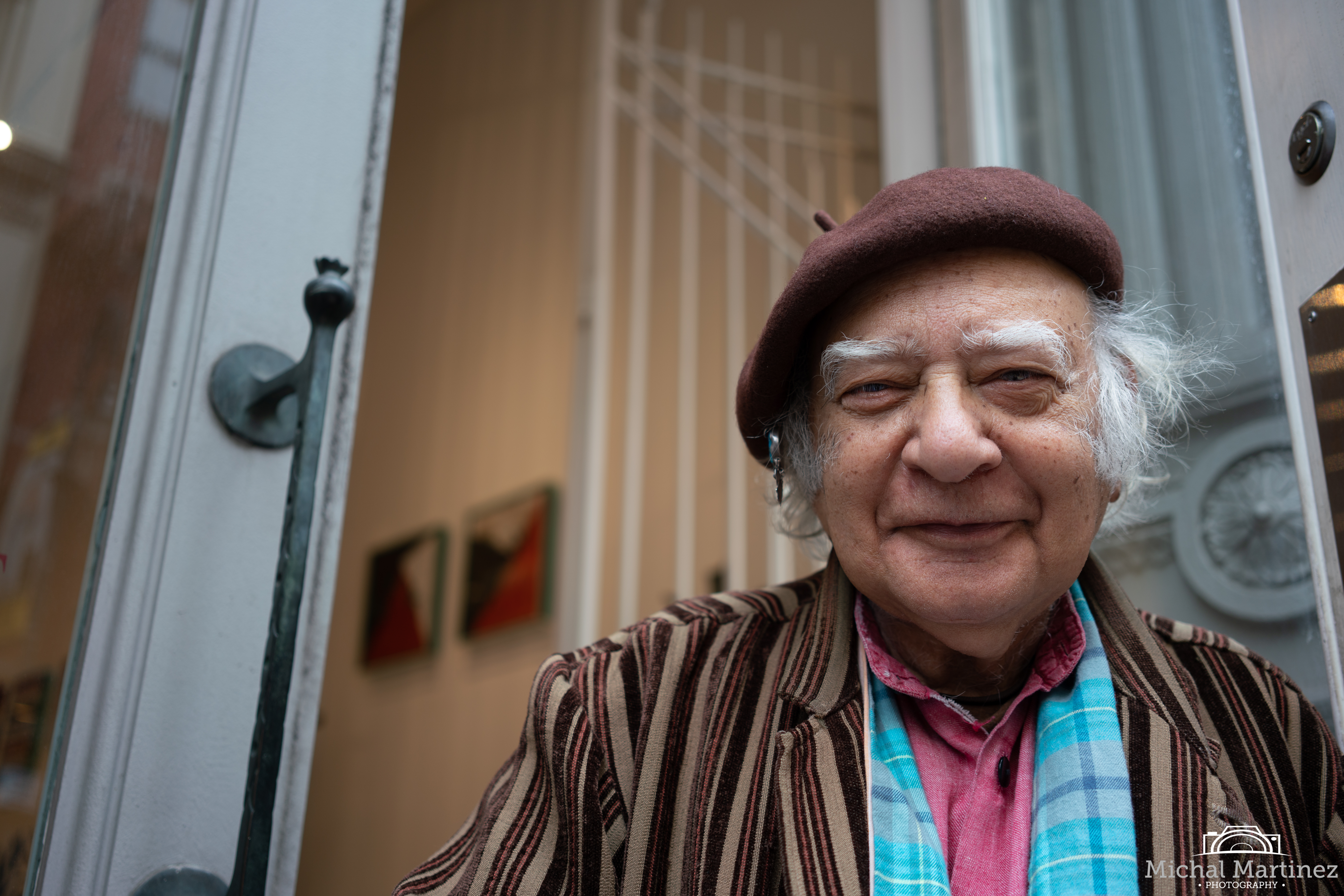 A happy older gentleman wearing a colorful outfit outside his gallery in NYC