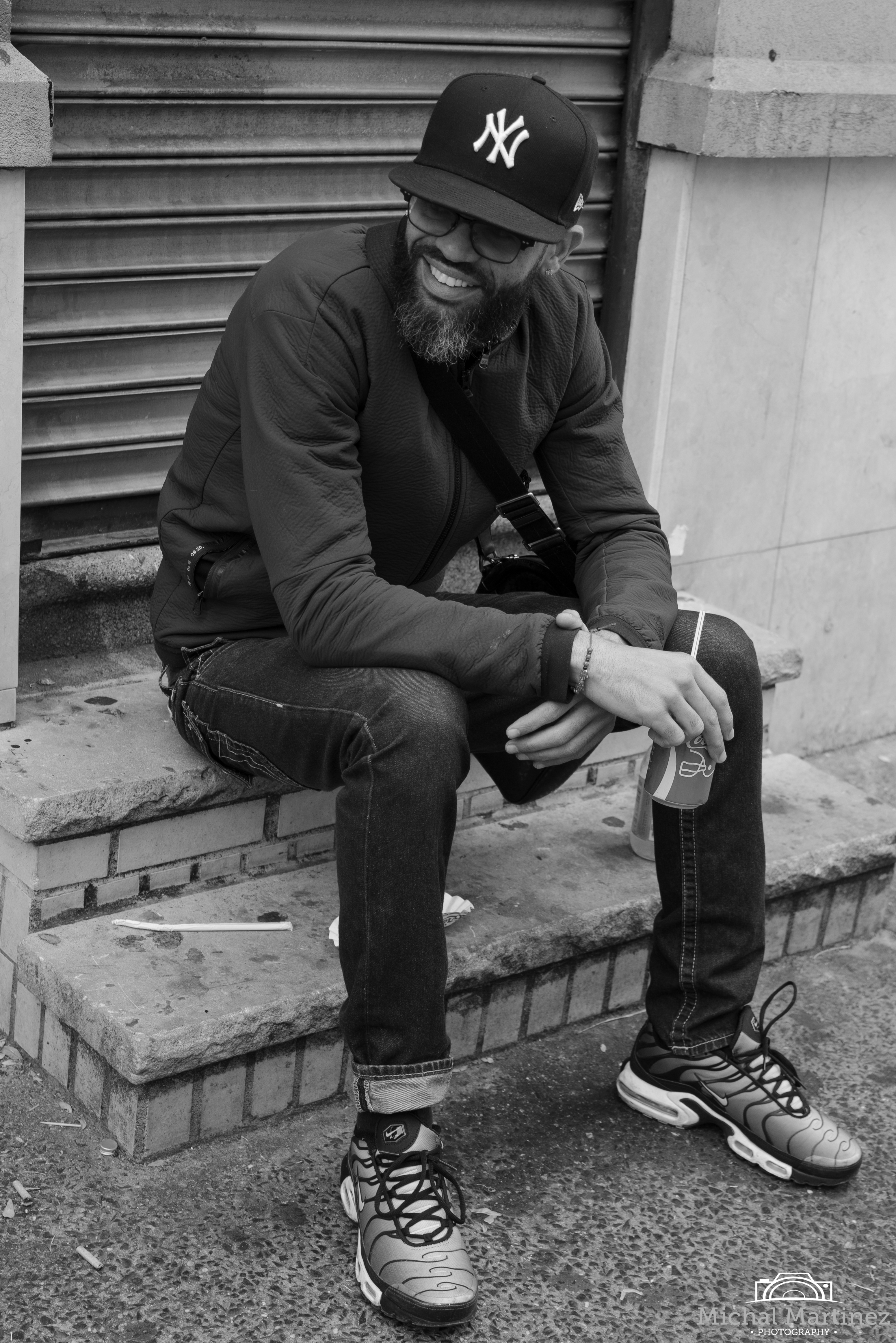 Young man sitting on steps drinking Coca Cola.
